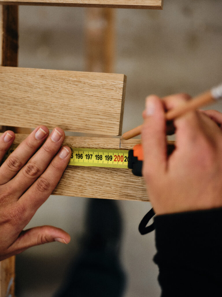 Katja Kammerer misst in der Werkstatt eine Holzlatte ab.