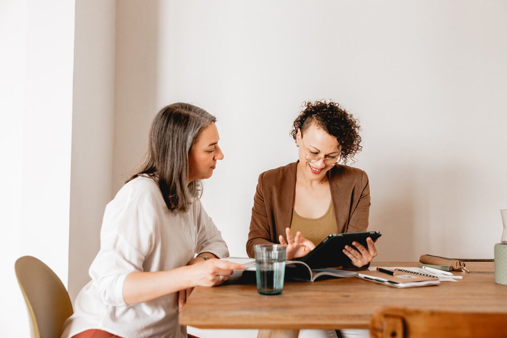 Eine Immobilienberaterin bespricht mit einem Kunden an einem Tisch die individuellen Anforderungen und Wünsche für den Kauf einer neuen Wohnung anhand einer Bedarfsanalyse.