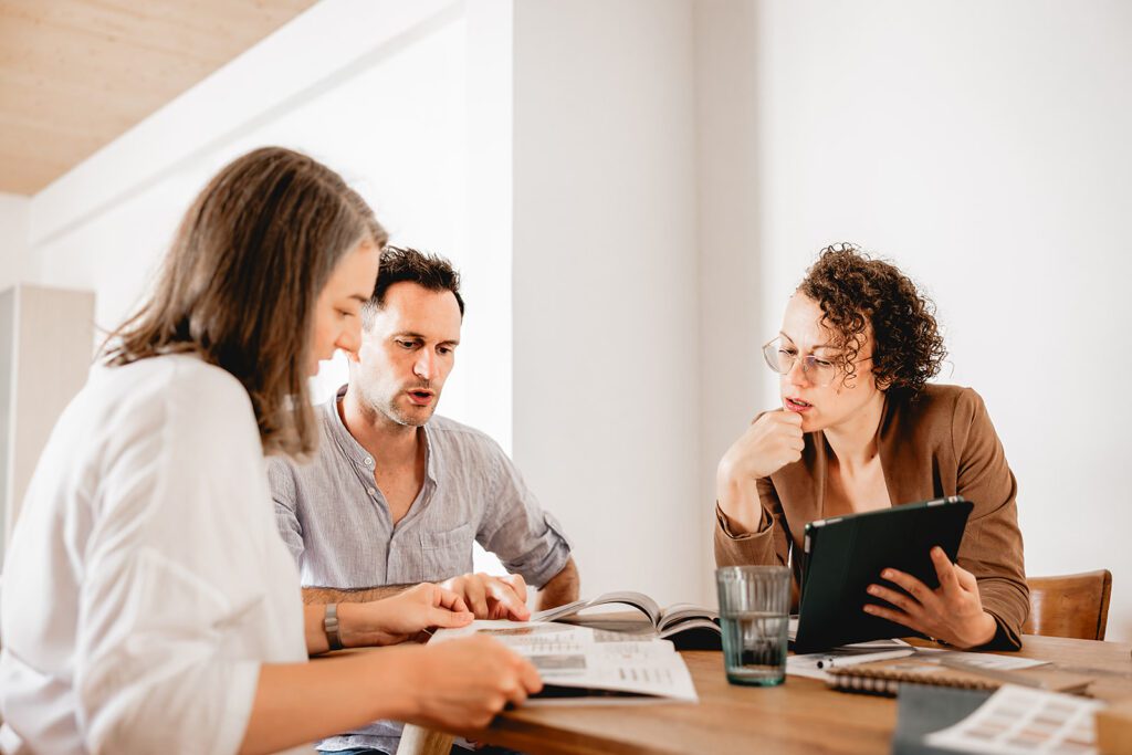 Beratungsgespräch zum Immobilienkauf: Beraterin analysiert gemeinsam mit Kunden Bedürfnisse und Anforderungen an die neue Wohnung.