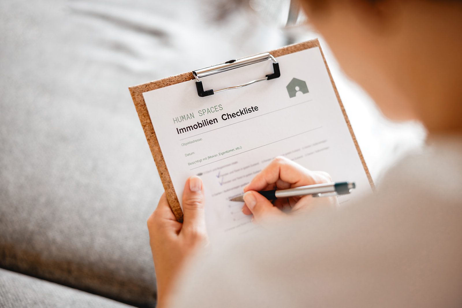 Eine Immobilienberaterin überprüft während einer Immobilienbesichtigung gemeinsam mit einem Kunden eine Checkliste zum Immobilienkauf.