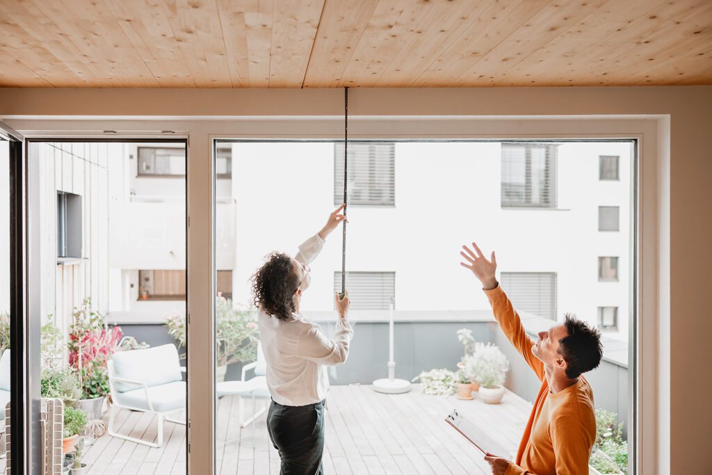 Eine Immobilienberaterin prüft gemeinsam mit einem Kunden bei einer Wohnungsbesichtigung die Baustruktur der Immobilie.